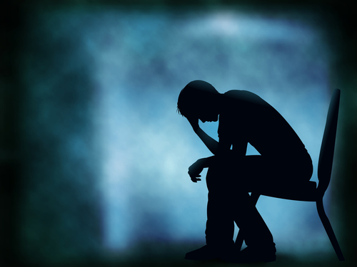 Editable vector silhouette of a man sitting with his head in his hand; background made with a gradient mesh
