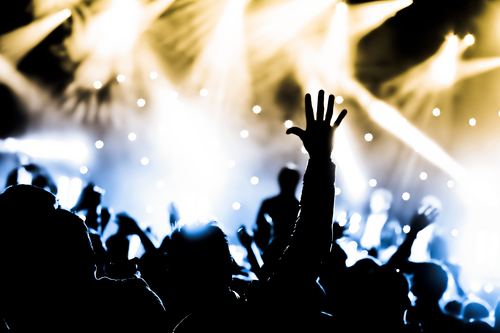 Crowd cheering with hands raised at a live music concert