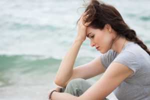 Close-up of a sad and depressed woman deep in though outdoors.