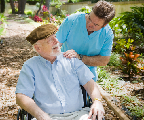 Disabled senior man in the garden with his male nurse.